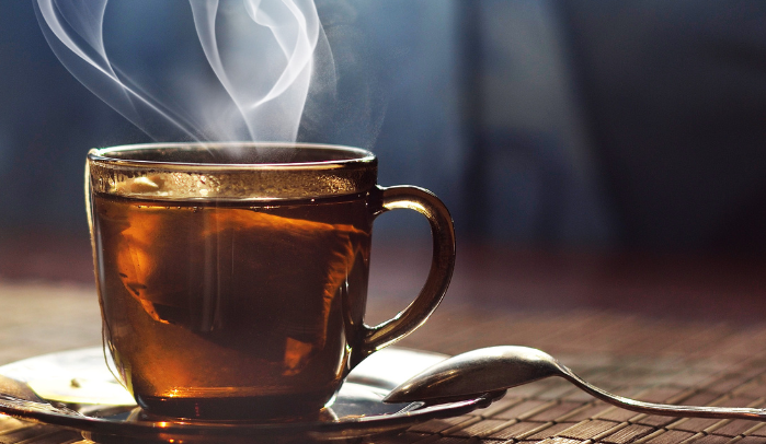 A steaming cup of herbal tea on a wooden table, representing natural remedies for pain relief and wellness.