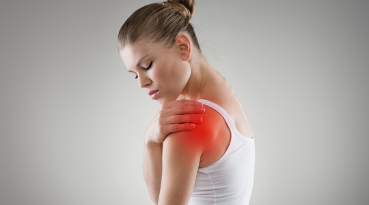Woman holding her shoulder in pain before acupuncture treatment at Acupuncture Heals in Mississauga