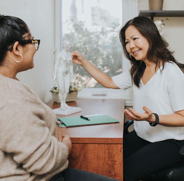 Dr. Thao Bui consulting with a patient during an acupuncture visit at Acupuncture Heals in Mississauga